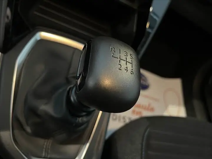Gros plan sur le levier de vitesses manuel noir de la Peugeot 208 gris Artense, intérieur sombre et console argentée visible.