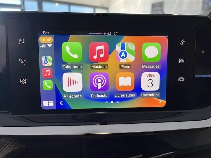 Écran tactile central de la Peugeot 208 2022 affichant Apple CarPlay avec icônes colorées, intérieur gris noir visible.