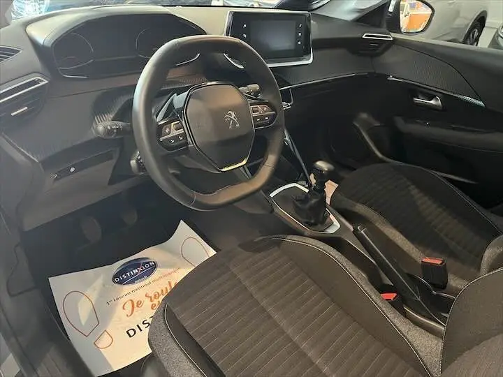 Intérieur de la Peugeot 208 gris Artense, vue côté conducteur montrant volant compact et console centrale avec boîte manuelle.