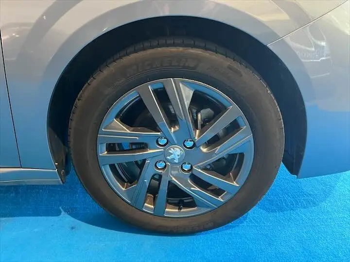 Gros plan sur la roue avant gauche gris Artense métal d'une Peugeot 208 1.2 100 CH S&S STYLE 2022 avec jante alliage moderne.