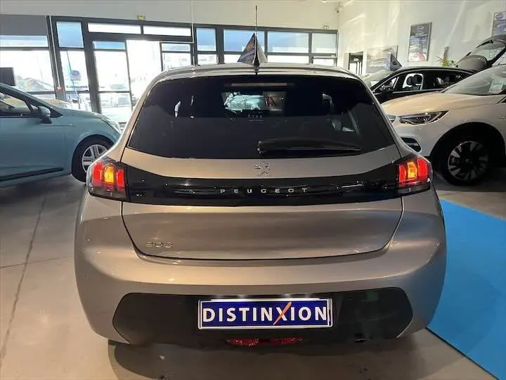 Vue arrière d'une Peugeot 208 gris Artense métal 2022 avec feux arrière allumés en concession.