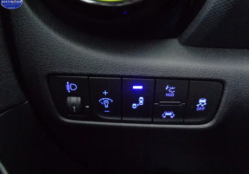 Gros plan sur les commandes éclairage et aides à la conduite du Hyundai Kona 1.6 CRDI jaune Acid Yellow, tableau de bord côté gauche.