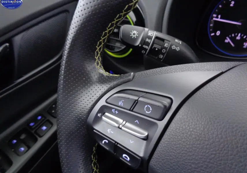 Gros plan sur le volant noir perforé avec surpiqûres jaunes du Hyundai Kona 2019, montrant les commandes audio et téléphone.