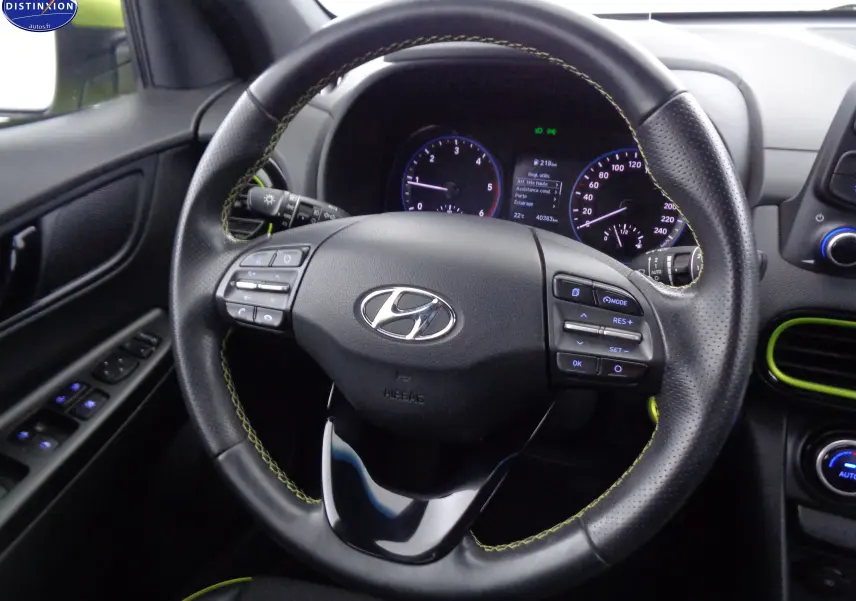 Vue rapprochée du volant en cuir noir avec surpiqûres jaunes du Hyundai Kona 2019, tableau de bord et détails intérieurs visibles.