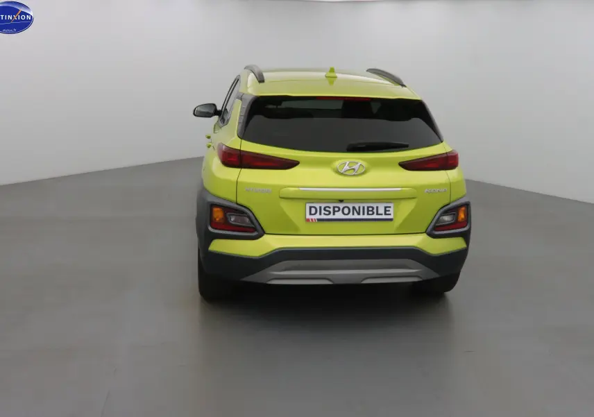 Vue arrière d'un Hyundai Kona 2019 jaune acidulé avec feux arrière étirés et plaque "DISPONIBLE" visible.
