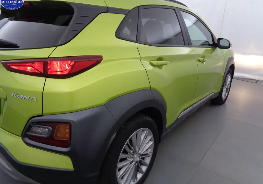 Vue 3/4 arrière droite d'un Hyundai Kona 2019 en vert acid yellow metal avec feux arrière allumés et protections noires.