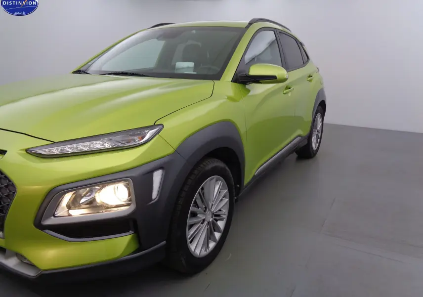 Vue 3/4 avant droit d'un Hyundai Kona 2019 en vert acid yellow metal avec phares allumés et jantes alliage.