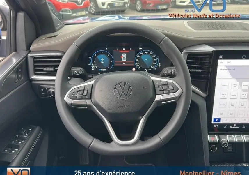 Vue intérieure centrée sur le volant cuir multifonctions du Volkswagen Amarok bleu 2025 avec écran digital et commandes intégrées.