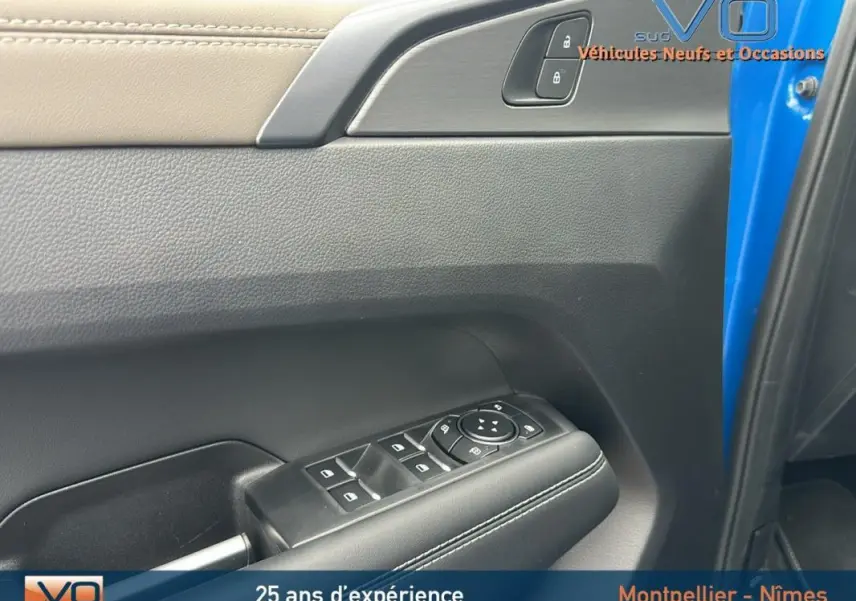 Vue rapprochée de la porte côté conducteur bleu du Volkswagen Amarok 2025, avec commandes de vitres et verrouillage.