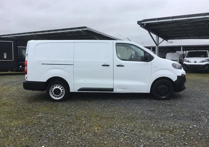 Vue de profil côté gauche d'un FIAT Scudo Fourgon blanc 2024 avec garde au sol réhaussée et protections tôlées.