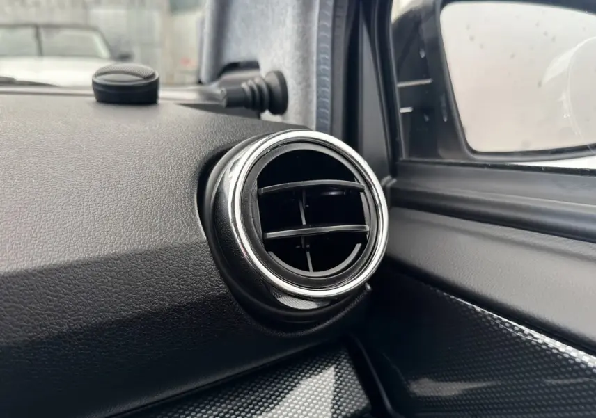 Détail de la sortie d’air ronde chromée côté conducteur dans l’habitacle de l’AIXAM AMBITION 0.5 CITY GTO blanc.