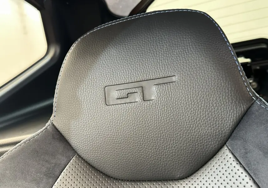 Gros plan sur l’appuie-tête noir embossé GT de l’AIXAM AMBITION 0.5 CITY GTO 2026, intérieur cuir et alcantara.