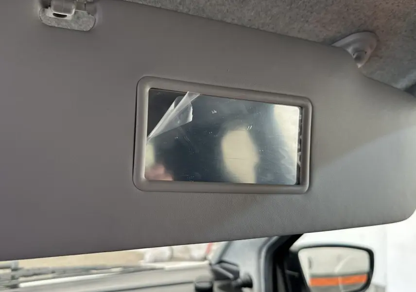 Miroir de courtoisie intégré au pare-soleil côté conducteur de l’AIXAM Ambition blanc, vue intérieure rapprochée.