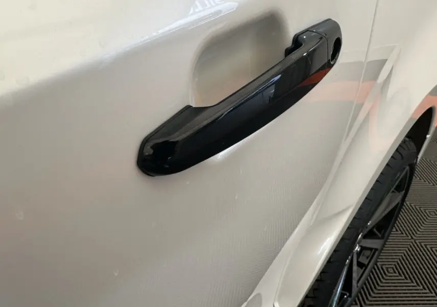 Gros plan sur la poignée de porte noire côté droit d'une Aixam Ambition 0.5 City GTO blanche de 2026.