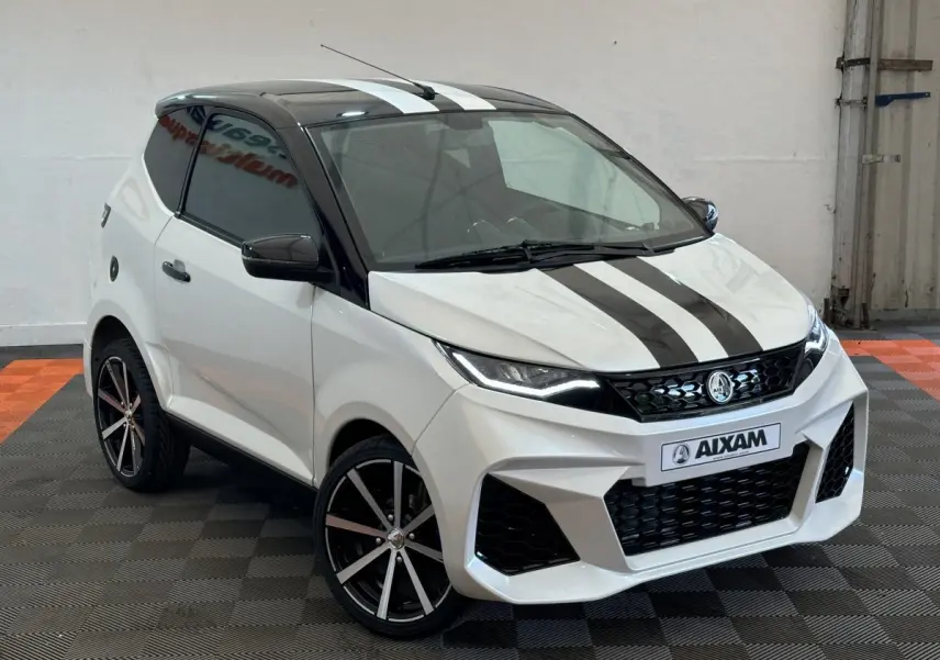 Vue 3/4 avant d'une Aixam Ambition 0.5 City GTO blanche avec toit noir et bandes noires sur le capot.
