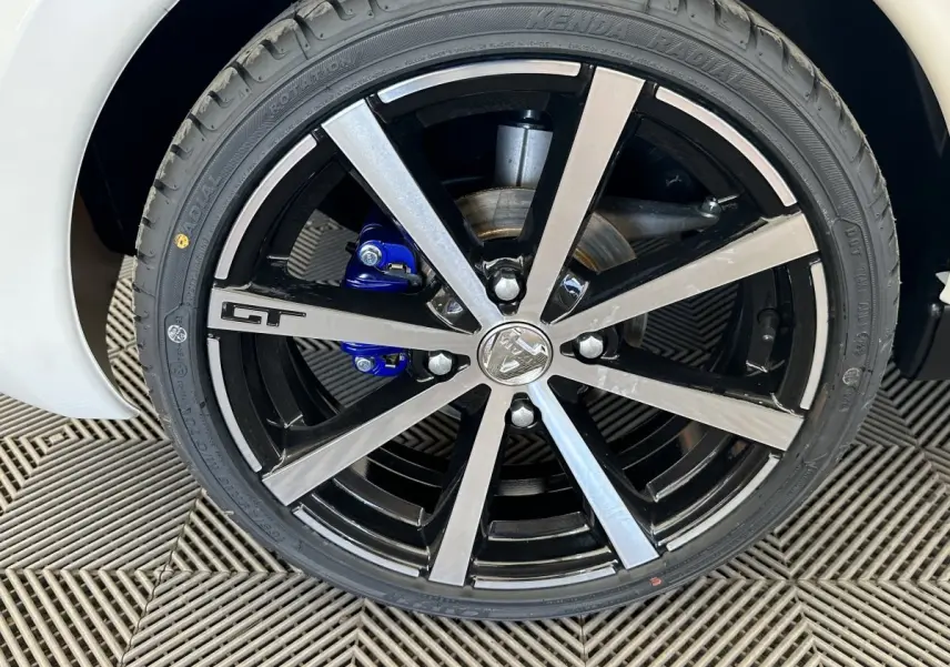 Gros plan sur la roue avant droite de l'AIXAM AMBITION 0.5 CITY GTO blanche, jante noire et argent avec logo GT.