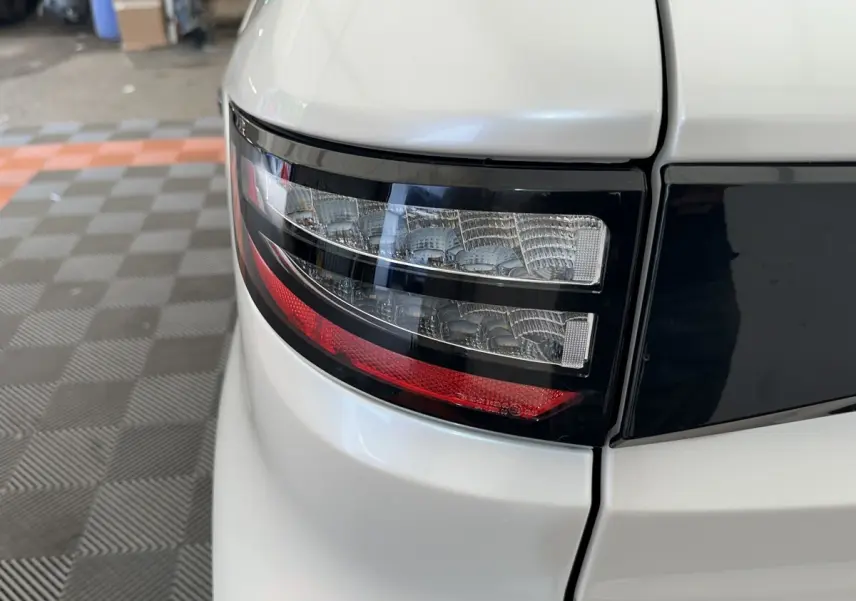 Gros plan sur le feu arrière droit blanc de l'AIXAM AMBITION 0.5 CITY GTO 2026 avec détails noirs et rouge.