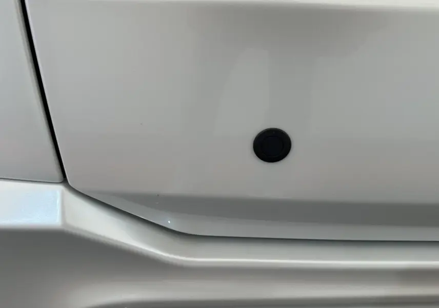 Détail du pare-chocs blanc de l'AIXAM AMBITION 0.5 CITY GTO 2026 avec capteur de stationnement noir.