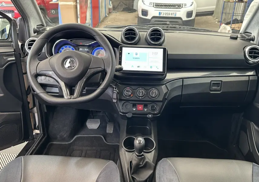 Vue intérieure frontale de l'AIXAM AMBITION 0.5 CITY GTO 2026 avec tableau de bord noir et écran tactile central.