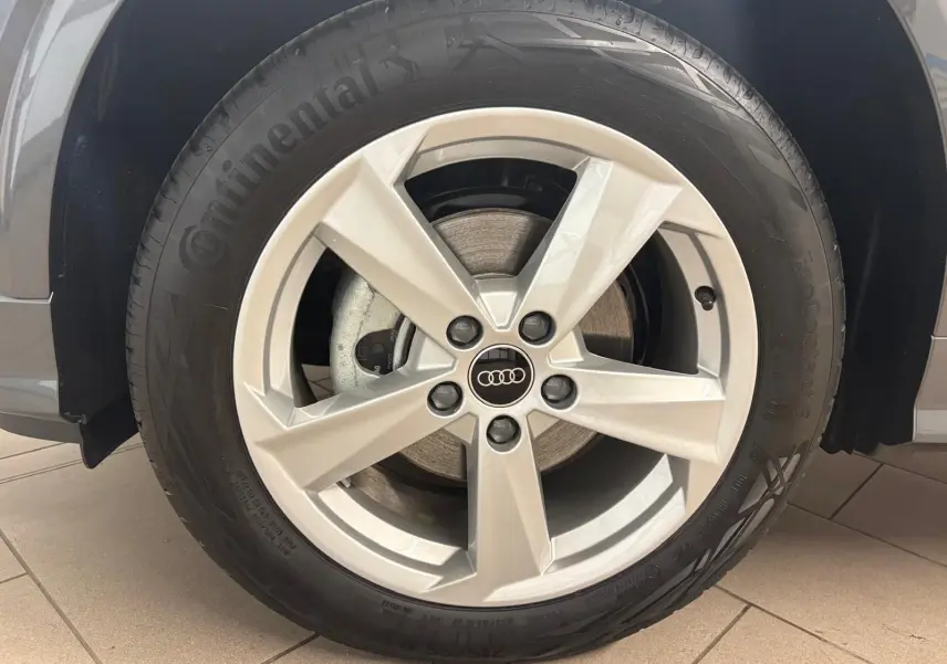 Gros plan sur la roue avant gauche de l'Audi Q2 35 TFSI S Line gris Daytona avec jante alliage cinq branches.