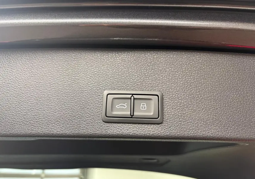 Boutons du hayon électrique et verrouillage intégrés sur la garniture intérieure du coffre d'un Audi Q2 gris Daytona 2026.
