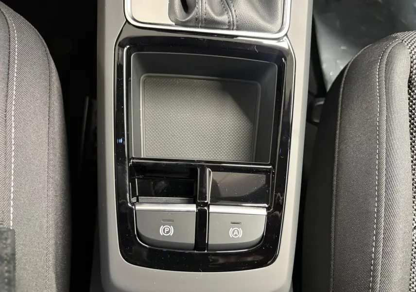 Gros plan sur la console centrale de l'Audi Q2 35 TFSI 150 S Line 2026, avec boutons de frein à main et auto hold.