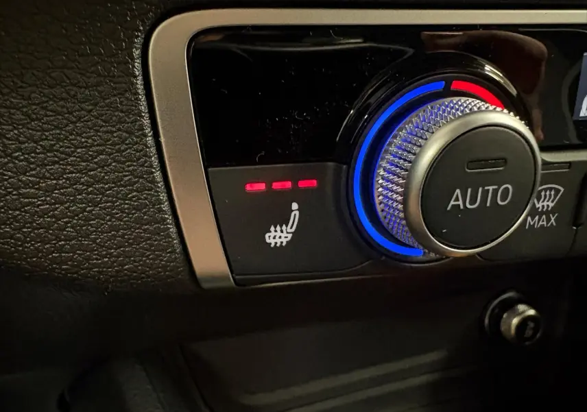 Gros plan sur la commande des sièges avant chauffants et du réglage automatique de la climatisation dans un Audi Q2 gris Daytona.