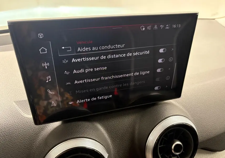 Écran central de l’Audi Q2 35 TFSI 150 S tronic 7 S line 2026 affichant les aides à la conduite, intérieur noir.