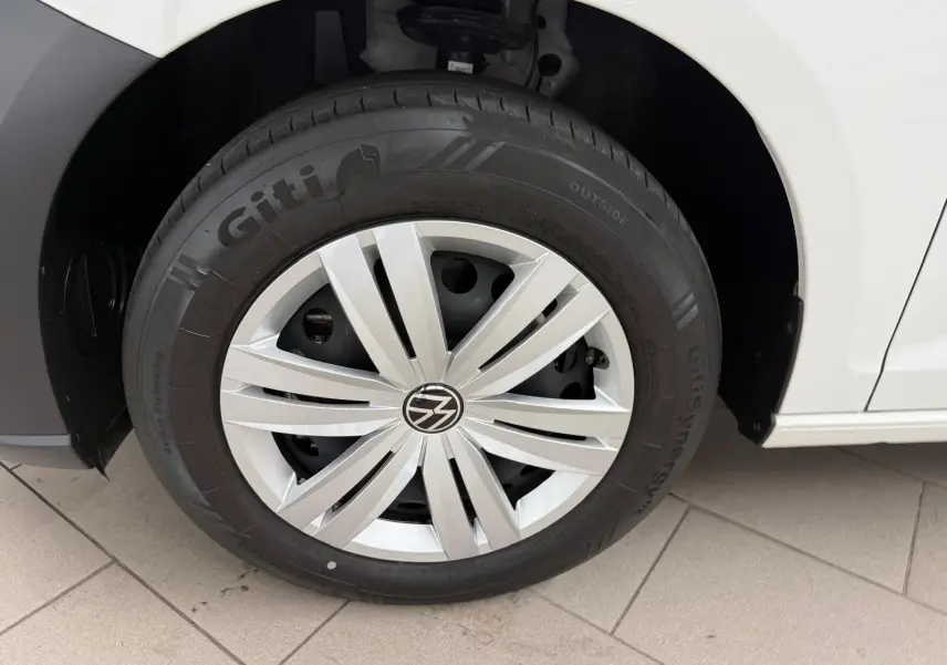 Gros plan sur la roue avant droite blanche du Volkswagen Caddy 2.0 TDI 122 DSG7 Business avec enjoliveur argenté.