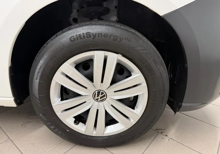 Gros plan sur la roue avant droite blanche du Volkswagen Caddy 2.0 TDI 122 DSG7 Business avec enjoliveur argenté.