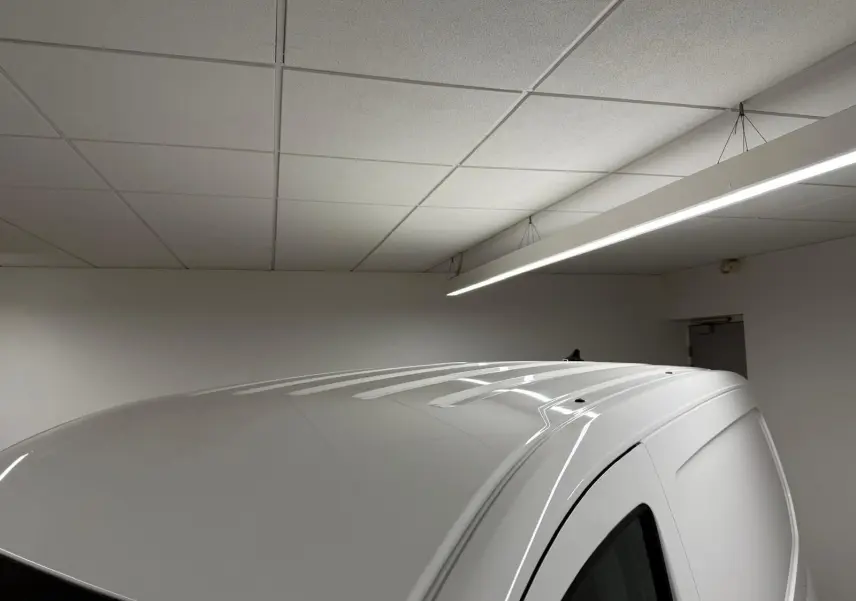 Toit blanc candy du Volkswagen Caddy 2.0 TDI 122 DSG7 Business vu en léger angle depuis l'arrière droit dans un garage.