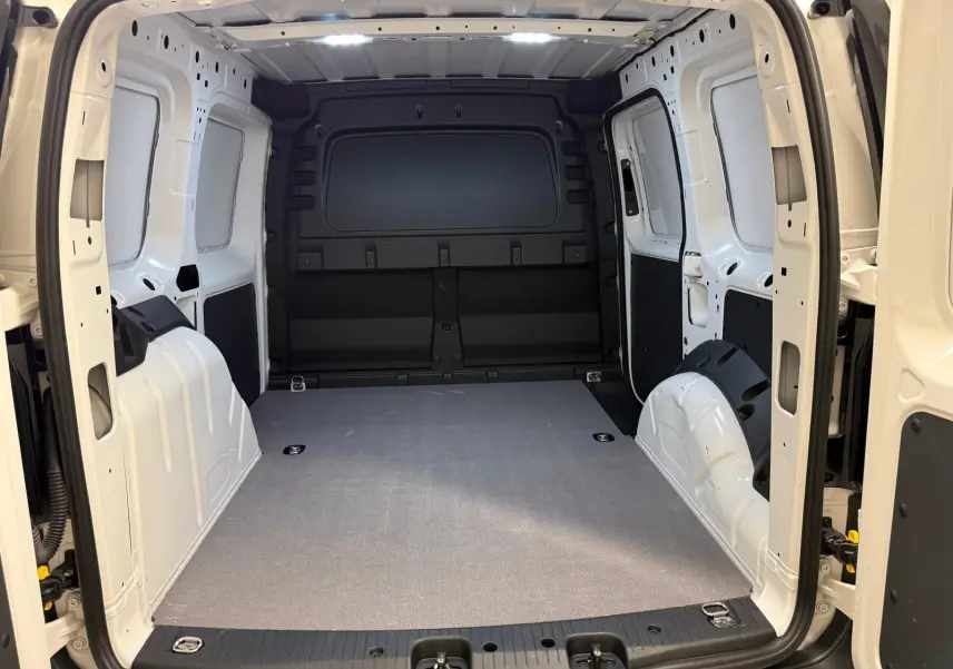 Vue intérieure arrière du Volkswagen Caddy blanc Candy 2025, montrant l'espace de chargement vide et les parois métalliques.