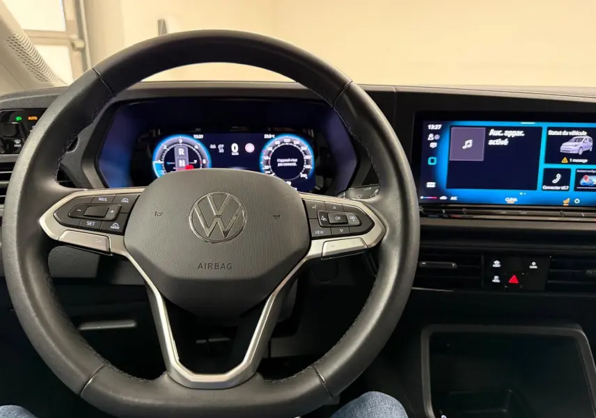 Vue intérieure centrée sur le volant cuir noir et le tableau de bord digital du Volkswagen Caddy 2025.
