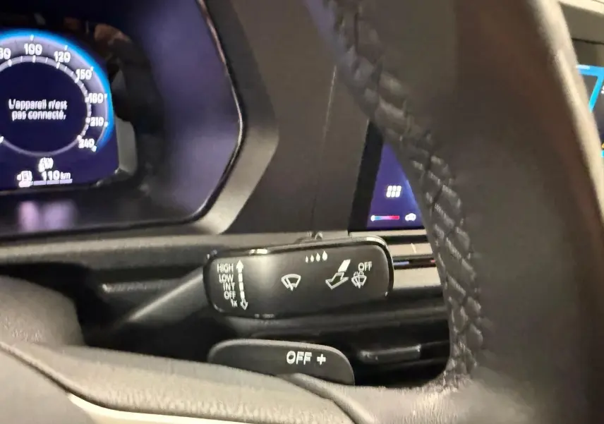 Gros plan sur la commande d’essuie-glace côté gauche du volant cuir du Volkswagen Caddy blanc 2025.