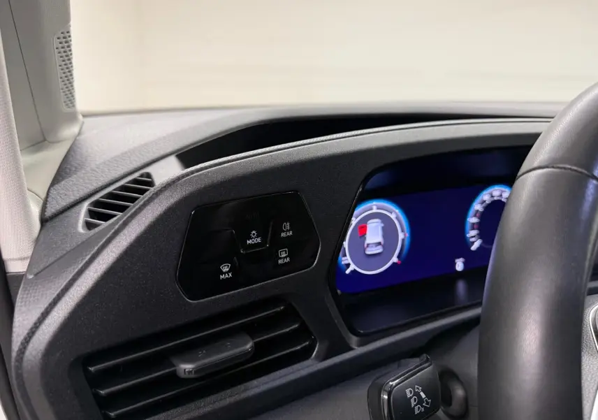 Vue intérieure du tableau de bord côté gauche du Volkswagen Caddy 2025 avec écran digital et commandes d'éclairage.