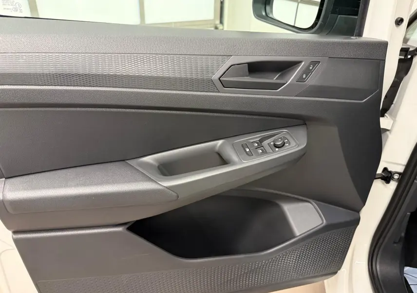 Vue rapprochée de la porte avant droite du Volkswagen Caddy blanc Candy, avec commandes électriques et poignée intégrée.
