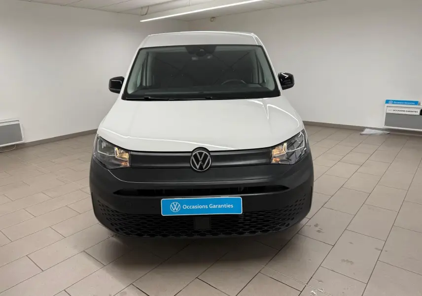 Vue de face du Volkswagen Caddy blanc Candy 2025 avec pare-chocs noir mat et logo VW central.