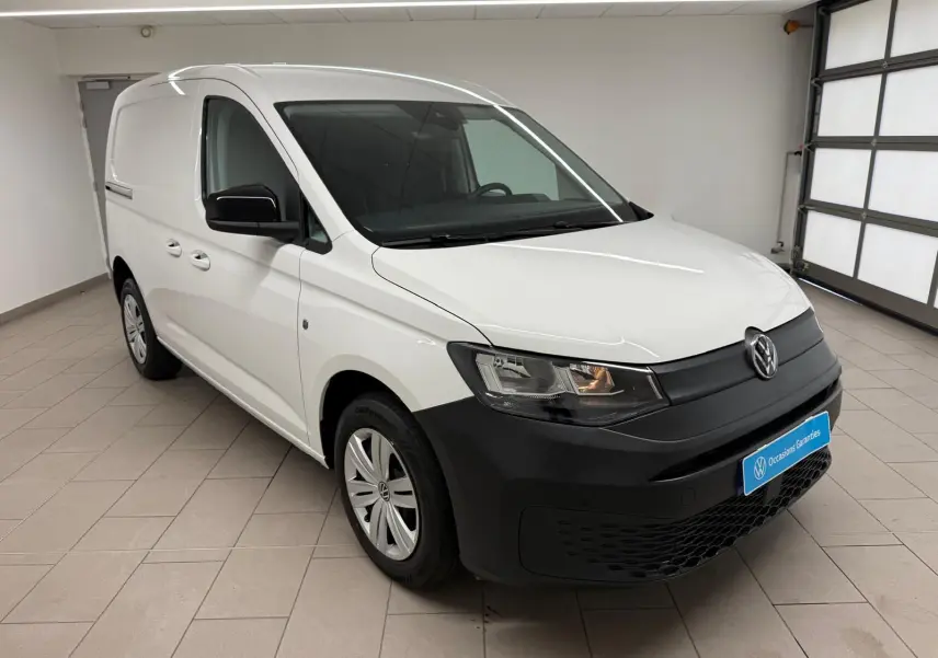 Volkswagen Caddy blanc candy vue 3/4 avant droit avec pare-chocs noir mat et jantes acier 16 pouces.