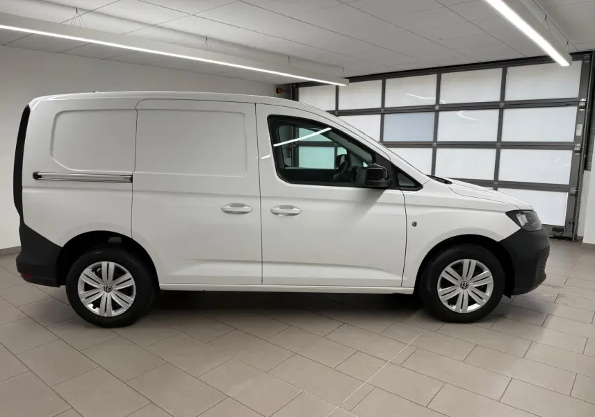 Vue de profil droit du Volkswagen Caddy blanc Candy 2025 avec pare-chocs noirs et jantes acier.