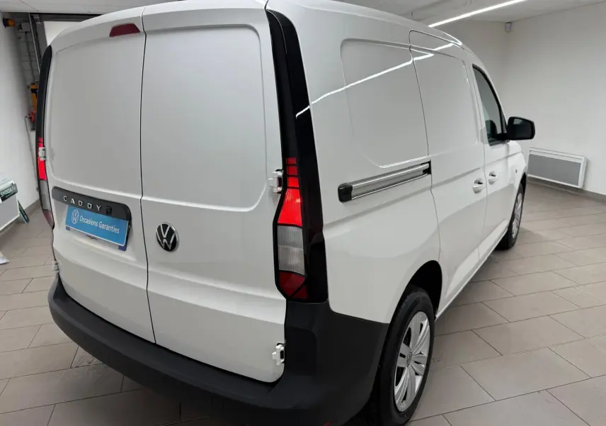 Vue 3/4 arrière droite d'un Volkswagen Caddy blanc Candy avec portes battantes arrière et pare-chocs noir mat.