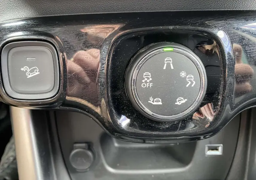 Gros plan sur le sélecteur de modes de conduite et le bouton d’aide à la descente dans l’habitacle du Citroën C3 Aircross gris.