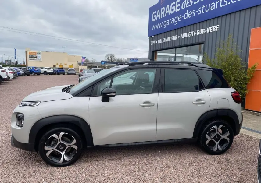 Vue de profil côté gauche d'une Citroën C3 Aircross grise 2020 avec toit noir et jantes distinctives bicolores.