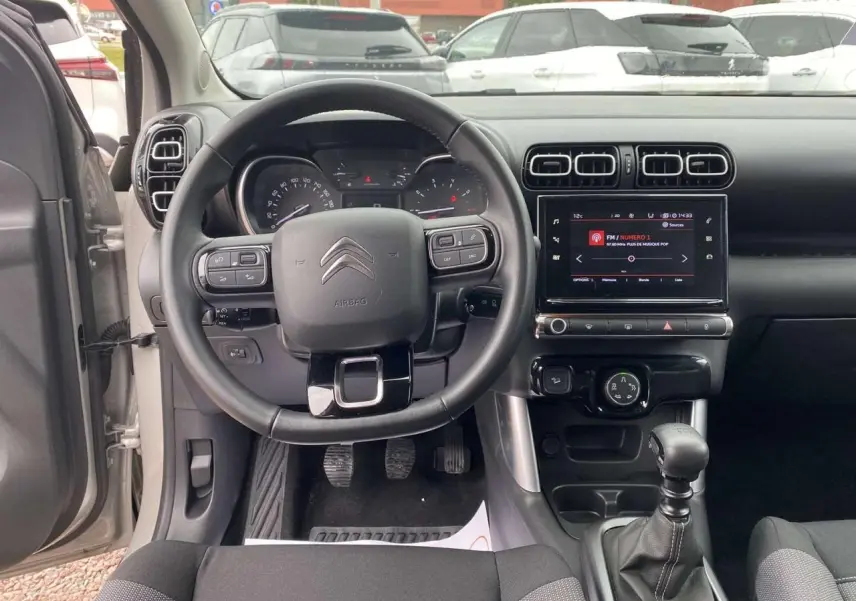 Vue intérieure frontale du tableau de bord gris du Citroën C3 Aircross 2020 avec volant multifonctions et boîte manuelle.