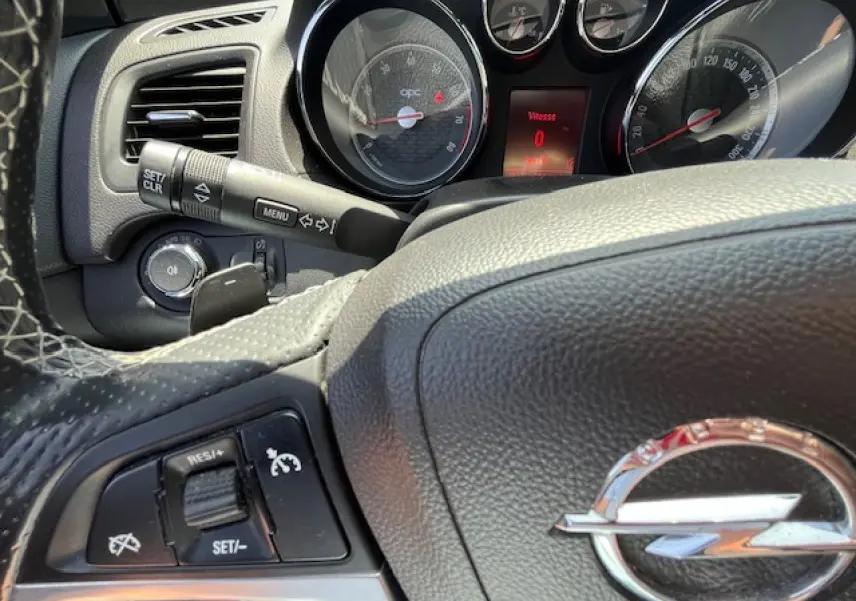 Vue rapprochée du volant et du tableau de bord de l'Opel Insignia Sports Tourer, avec logo Opel et commandes au volant visibles.