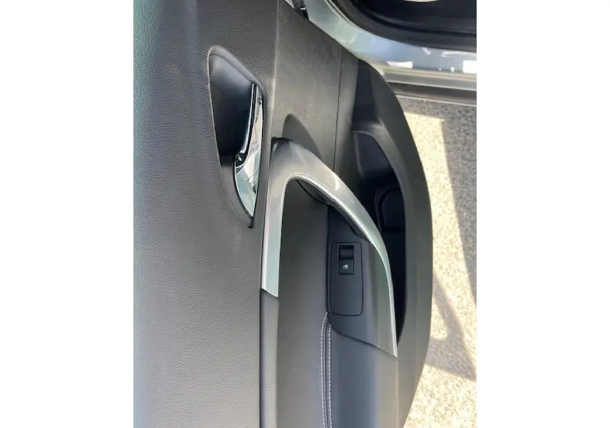 Gros plan sur la poignée intérieure chromée et la commande de verrouillage de la porte côté avant droit d’une Opel Insignia Sports Tourer gris clair.