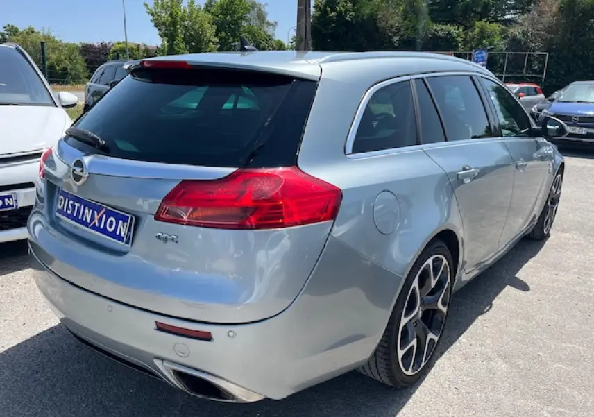 Vue 3/4 arrière droite d'une Opel Insignia Sports Tourer gris clair avec jantes alliage 20'' et double sortie d'échappement chromée.