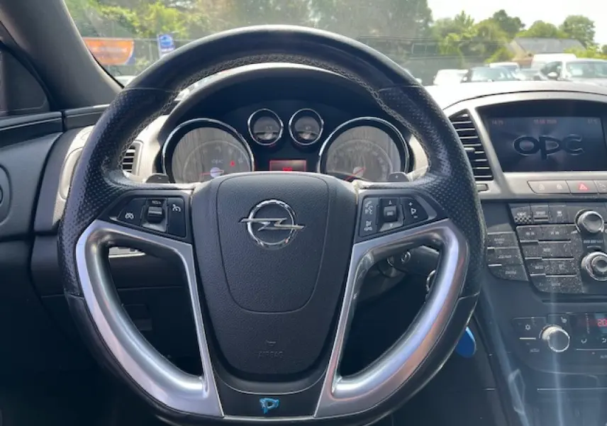 Vue intérieure centrée sur le volant noir perforé de l’Opel Insignia Sports Tourer avec tableau de bord et écran OPC.
