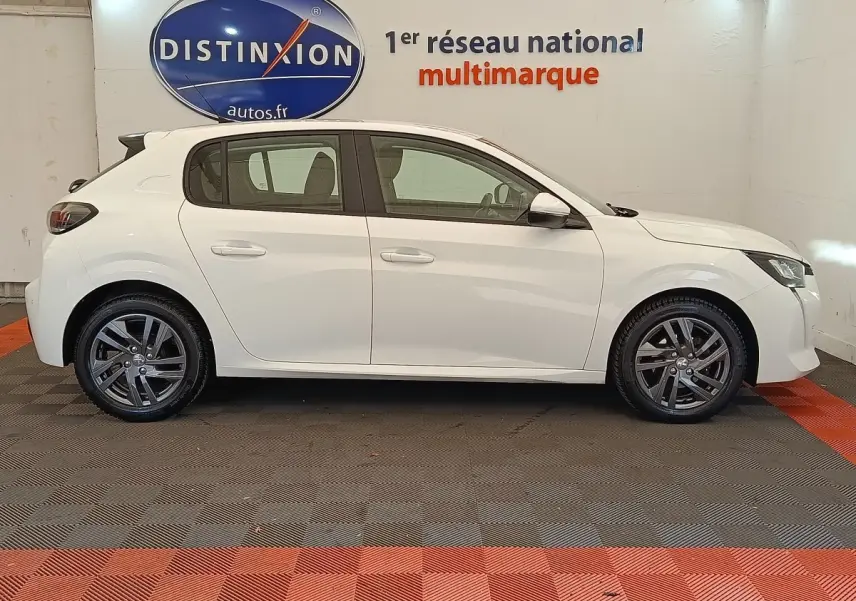 Profil latéral droit d'une Peugeot 208 blanche de 2021, avec jantes alliage et rétroviseurs électriques rabattables.