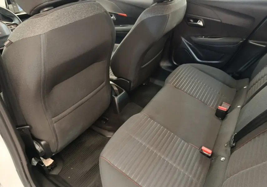 Vue arrière des sièges arrière noirs avec surpiqûres rouges dans une Peugeot 208 PureTech 75 S&S Active Business blanche.