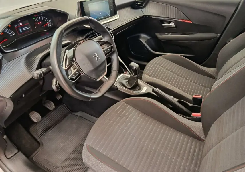 Vue intérieure côté conducteur de la Peugeot 208 blanche, volant cuir multifonctions et écran tactile central visible.